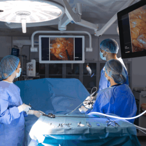 Tela de monitor exibindo o procedimento de uma histerectomia por videolaparoscopia, com foco nos instrumentos cirúrgicos.